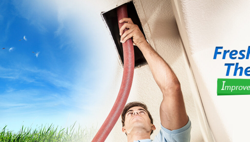 A man holding up an air hose to the vent of a house.
